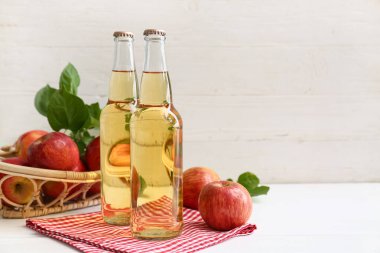 Beyaz ahşap arka planda elma şarabı şişeleriyle taze meyveler.