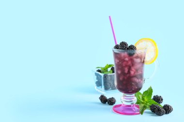 Lezzetli böğürtlenli limonata ve mavi arka planda malzemeler.