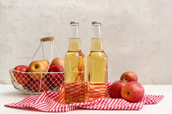 Taze elma şarabı şişeleri ve beyaz arka planda meyveler