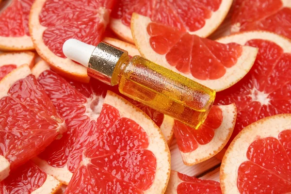 Greyfurt dilimlerinin üzerinde bir şişe gerekli yağ.