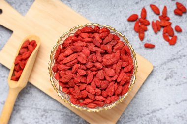 Gri grunge arka planda kurutulmuş goji üzümleri ile kase ve kepçe, yakın plan