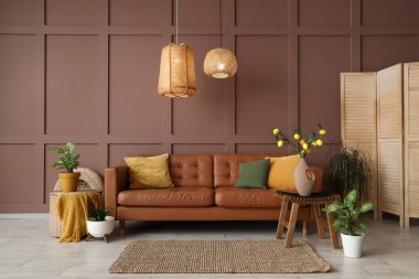 Rahat kahverengi kanepesi, çiçekleri ve hasır lambaları olan şık bir oturma odası.