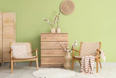 Hasır koltuklar, çekmeceler ve vazolar. Oturma odasının iç tarafında pamuk çiçekler var.