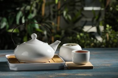 Çaydanlıklı tepsi ve dışarıdaki ahşap masada sıcak çay.