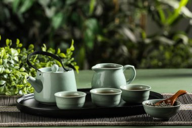 Çaydanlıklı tepsi, sürahi ve yeşil masada bir fincan çay.