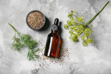 Gri zemin üzerinde bir şişe dereotu tohumu.