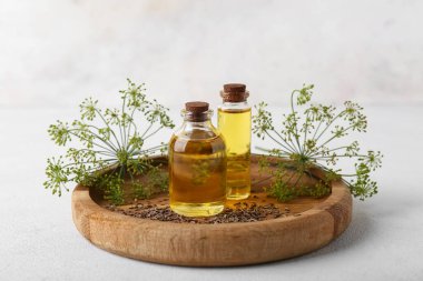 Tahta tabakta beyaz zemin üzerinde dereotu tohumu şişeleri var.