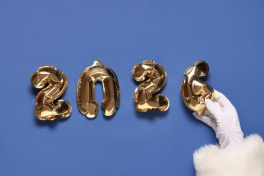 Noel Baba eli, arka planda folyo balonlardan yapılmış 2026 figürlü.