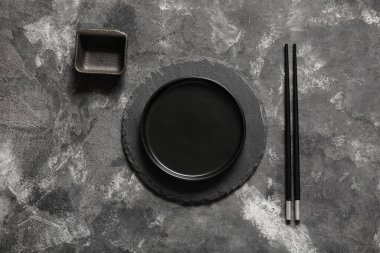 Gri arka planda tabak ve sos kasesiyle Çin sofrası.