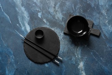 Tabak, kase ve çubuklarla dolu Çin sofrası grunge mavi arka planda.