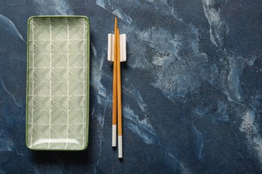 Çin sofrasında tabak ve yemek çubuklarıyla grunge blue background