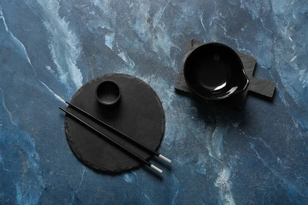 Tabak, kase ve çubuklarla dolu Çin sofrası grunge mavi arka planda.