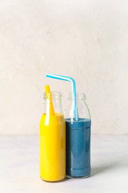 Beyaz masada cam şişeler dolusu sarı ve mavi smoothie