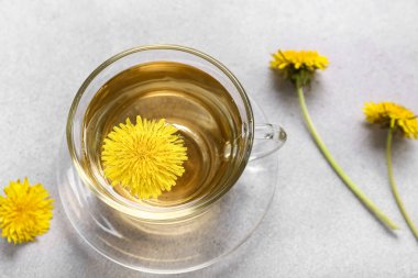 Gri arkaplanda bir bardak sağlıklı karahindiba çayı.