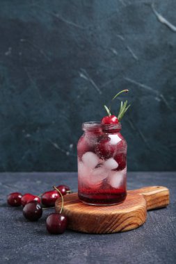 Koyu arkaplanda kirazlı limonata ve biberiyeli ahşap tahta tabela.