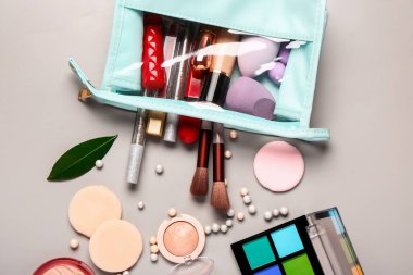 Gri arkaplanda makyaj ürünleri bulunan şık kozmetik çanta