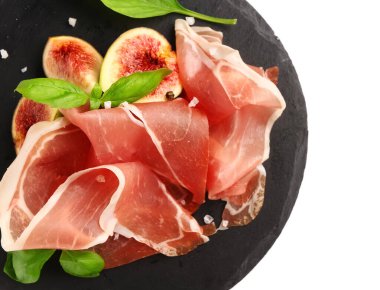 Beyaz arka planda lezzetli prosciutto, fesleğen ve incir dilimleri olan bir tahta.