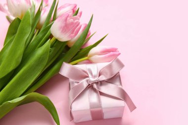 Pembe arka planda laleleri olan hediye kutusu.