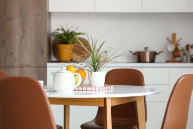 Meyveli çaydanlık ve mutfak masasında bitki.