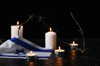Yakıcı mumlar, dikenli teller ve arka planda İsrail bayrağı. Soykırım Anma Günü
