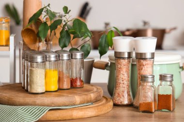 Farklı baharatlı kavanozlar, çatal bıçaklar ve mutfak masasında bitki, yakın plan.