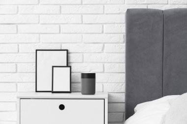 Yatak odasındaki beyaz tuğla duvarın yanındaki masada boş çerçeveli hava nemlendirici.