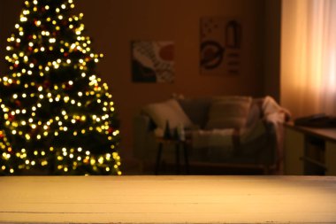 Geceleri oturma odasında parlayan güzel Noel ağacının yanında kanepesi olan ahşap masa, yakın plan.