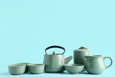 Mavi arka planda çay, kase ve sürahi olan çaydanlık.