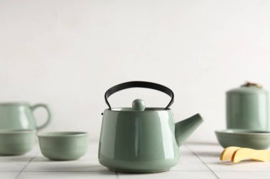 Çay fincanları ve beyaz fayans üzerinde bambu maşası olan çaydanlık.