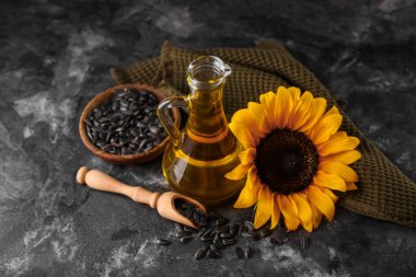 Siyah grunge arka planda ayçiçeği yağı, çiçek ve tohumların dekanı, yakın plan