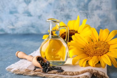 Mavi grunge arka planında ayçiçeği yağı, peçete ve tohum kepçesi, yakın plan