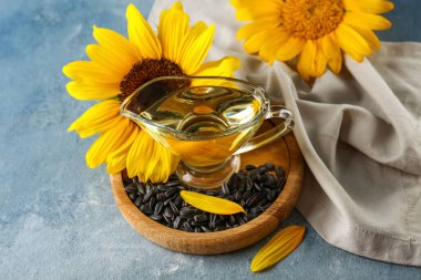 Ahşap tepsi, cam sürahi ayçiçeği yağı ve mavi grunge arka planda tohumlar, yakın plan.