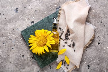 Tepsiyle kompozisyon, bir şişe ayçiçeği yağı ve grunge arkaplanda tohumlar, yakın plan.