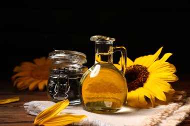 Kahverengi ahşap arka planda ayçiçeği yağı ve bir kavanoz tohum, yakın plan.