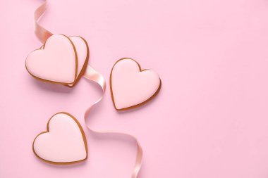 Tatlı kalp şeklinde kurabiyeler ve pembe arka planda kurdele. Sevgililer Günü kutlaması