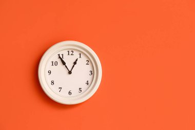 Turuncu duvarda asılı şık bir saat