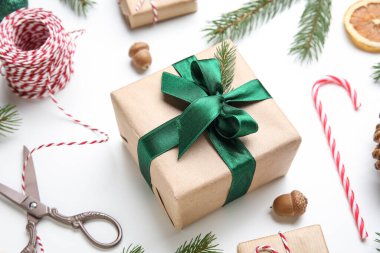 Noel kompozisyonu hediye kutuları, köknar ağacı dalı, beyaz arka planda iplikler ve makas, yakın plan