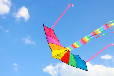 Güneşli bir günde mavi gökyüzünde uçan renkli uçurtma