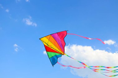Güneşli bir günde mavi gökyüzünde uçan renkli uçurtma
