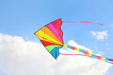 Güneşli bir günde mavi gökyüzünde uçan renkli uçurtma