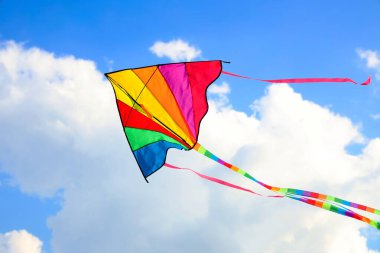 Güneşli bir günde mavi gökyüzünde uçan renkli uçurtma