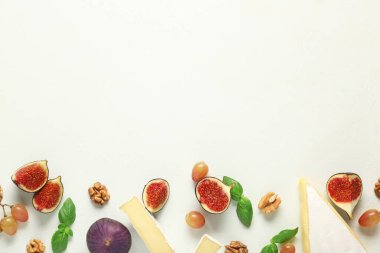 Beyaz arka planda lezzetli Camembert peyniri, üzüm ve taze incir parçaları ile kompozisyon