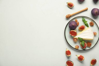 Beyaz arka planda bir parça Camembert peyniri, üzüm ve taze incir.