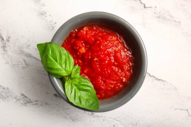 Lezzetli domates soslu bir kase mermer arka planda, yakın plan.