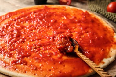 Hamur hamuru pizza, ahşap arka planda domates sosu, yakın plan.