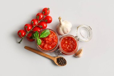 Lezzetli domates soslu cam kavanozlar ve beyaz arka planda malzemeler.