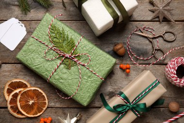 İple Noel hediyesi kutuları, kurutulmuş portakal dilimleri, makas ve ahşap arka planda yaban mersini.