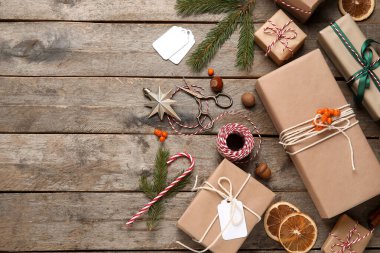 İp, makas, köknar ağacı dalları ve ahşap arka planda yabanmersini dolu Noel hediyesi kutuları.