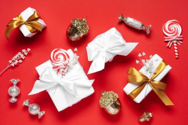 Farklı Noel süslemeleri ve kırmızı arka planda hediye kutuları olan güzel bir kompozisyon