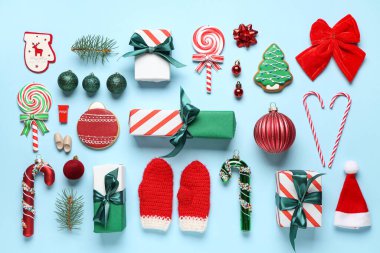 Hediye kutuları, Noel topları, kurabiyeler ve mavi arka planda baston şekerler.